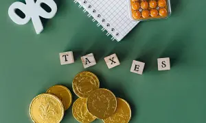 Złote monety, kalkulator i kostki z napisem "TAXES" sugerują rozważania o zakupie złota a podatek PCC.