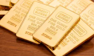 Sztabki złota Credit Suisse, każda o wadze jednej uncja trojańska, błyszczą na drewnianym tle.