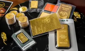 Stos monet i sztabek z czystego złota, w tym 100g i 500g sztabki Heraeus i Chafner. Widać też złote ozdoby w kształcie węża.