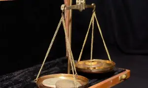 Złota waga szalkowa z monetami na jednej szalce. Czy to jest ile to jedna uncja?
