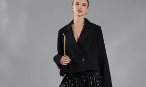 Modelka w czarnej marynarce i błyszczącej spódnicy z cekinami.
