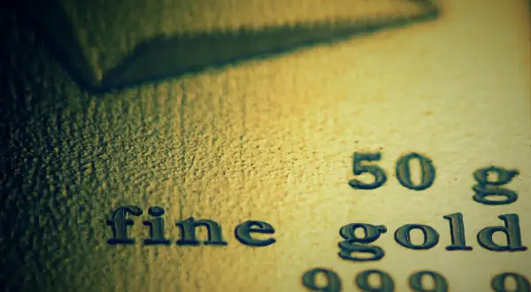 Zbliżenie na tekst "fine gold 50 g 999,9" wybity na powierzchni złota.