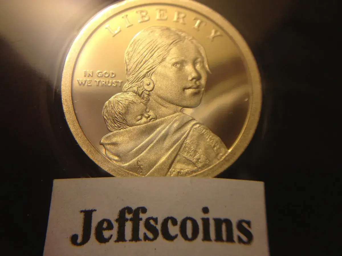 Złota moneta z wizerunkiem kobiety i dziecka, z napisem "Liberty" i "In God We Trust".