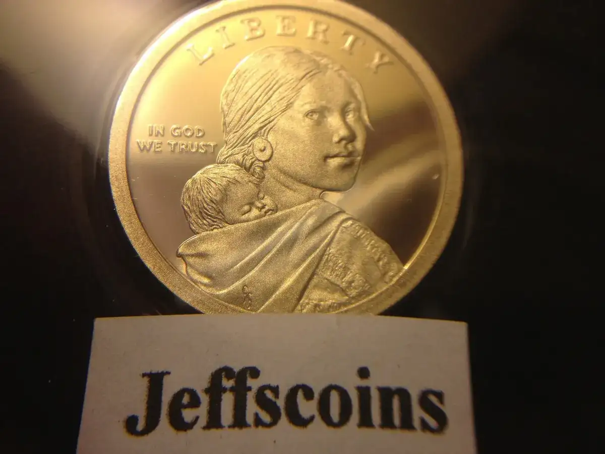 Złota moneta z wizerunkiem kobiety i dziecka, z napisem "Liberty" i "In God We Trust".